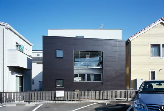 白い建物をぐるりと囲むように設けた黒い壁。白い壁と黒い壁の開口部の位置をずらし、採光とプライバシーを両立した。黒い壁の高さ、開口部の位置は、子世帯、親世帯それぞれの身長から細かくシミュレーションして決めている。