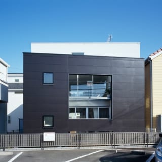 白い建物をぐるりと囲むように設けた黒い壁。白い壁と黒い壁の開口部の位置をずらし、採光とプライバシーを両立した。黒い壁の高さ、開口部の位置は、子世帯、親世帯それぞれの身長から細かくシミュレーションして決めている。