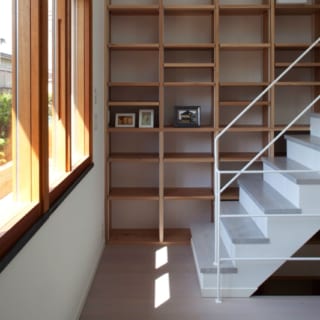 2階　書棚／ダイニングの一角には3階への階段がある。階段横の壁に造り付けた大きな書棚は自由な発想で使えるが、何も置かなくても絵になる。木製サッシと好相性の御影石の窓台もインテリアのポイント