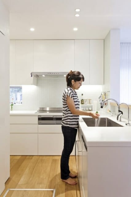1階キッチン／オーダーでつくったキッチンは、清潔感のある白で統一。作業台の高さは奥さまの身長に合わせている。壁のタイルは透明感のあるガラスタイル