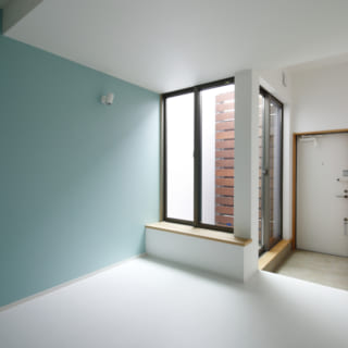 賃貸部分のリビングルームは玄関一体型。限られた面積を有効活用している。窓と木製ルーバーの間に光庭を設け、実際の面積以上の開放感を創造している。