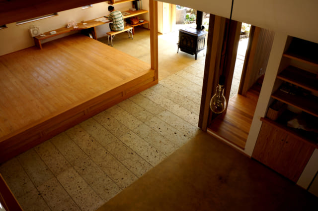 ロフトから見下ろす食堂と居間。土間の床は、深岩石と真砂土三和土仕上げ。板間の床は杉縁甲板の4㎝と厚くしっかりしたもので、踏み心地がよく調湿性・保温性も高い