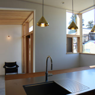 開放感あるオープンキッチンはチーク材を使用して造作。コンクリートの土間のホールやダイニング空間を見渡せる