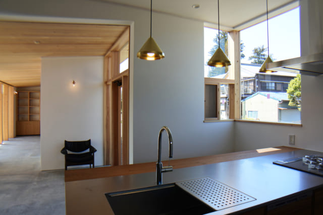 開放感あるオープンキッチンはチーク材を使用して造作。コンクリートの土間のホールやダイニング空間を見渡せる