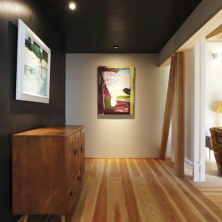 ダイニングとリビングをつなぐギャラリースペース。正面と左手に飾られている絵画もＫさんお気に入りの岡野博氏の絵画作品。右手に見えるのは除湿型放射冷暖房（ピーエス）。ちなみにこの家では次世代省エネ基準をクリアする性能を確保した上で、ここと寝室の2箇所に放射冷暖房を設置し、主な生活スペースの環境を穏やかにコントロールしている