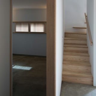 寝室の隣には2階に続く階段を配置。土間のモルタルと階段の木の風合いが違和感なく組み合わされている