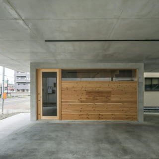木枠、杉板貼りで、引き戸になっている玄関は、防犯性の高い電子錠を採用。杉板貼りの壁の中央は開閉式になっており、開けると網戸に。中間期は、ここを開けることで建物全体の風通しをよくしてくれる