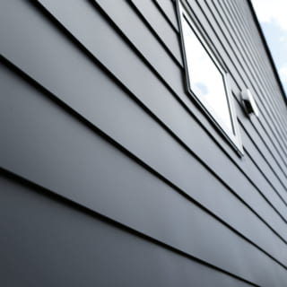 外壁は屋根材と同じガルバリウム鋼板を採用。横に長いガルバリウム鋼板の一枚板を上下に並べて張っていくことで横のラインが際立ち、横に大きく広がる背景の多度山の雄姿とのバランスもいい