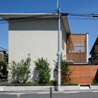 敷地は、東西北が道路に面する角地。建物の背面にあたる南側は隣家が迫り採光を望みにくい。そこで、敷地の南側に広いデッキを設け、デッキに入る光が家中に行きわたるプランで採光を確保。その分、道路面は壁が多くなったが、植栽によっていきいきとした表情を加えている