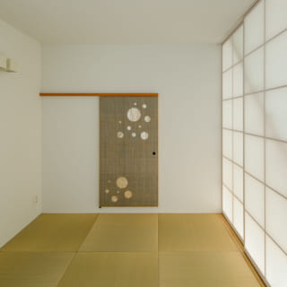 和室は、リビング・ダイニング側の障子を閉めると独立した空間になる。写真正面の引き戸は茶室の躙り口（にじりぐち）をイメージして小さめにつくった。青く塗装した木材に麻を張っているため独特の色彩に。日本画を飾っているかのようで、インテリアのポイントになっている