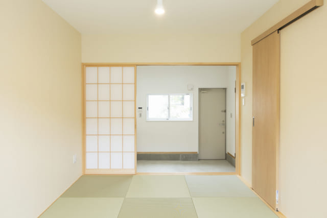 105号室。琉球畳の洒落た和室で床座の生活ができる。右奥の玄関ドアを開けるとほかの学生さんも通る中庭なので、広い土間をつくって中庭と住空間の距離を確保した
