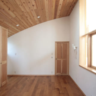 アーチ屋根の曲線がよくわかる2階主寝室もトップライト付き。木製の扉やクロゼットも床材と同じバーチ材
