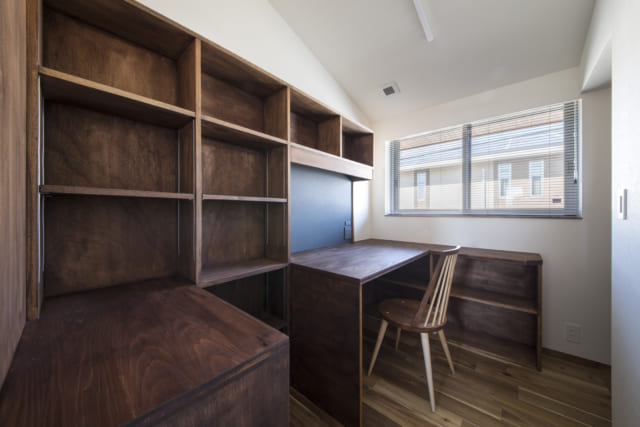 デスクと壁一面の本棚を備えた2階の書斎スペース。手作り感のある造作家具が温かい雰囲気を醸し出している