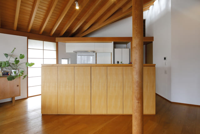 リビング脇のアイランドキッチンは、内装と統一感のあるオリジナル製。キッチン奥には、寝室などのプライベートスペースが広がる