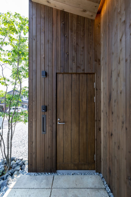 玄関の木製ドアは既製品だが、武骨な枠をうまく隠したことで遠目からは一枚板のように見える