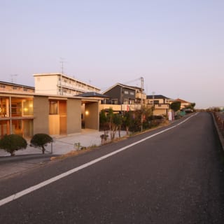 多摩川沿いの堤防道路から2mほど下がった敷地に立つS邸。どっしりと地面に根付く平屋づくりの外観が、おおらかな自然風景に馴染んでいる。シンプルなアウトラインとレイヤー状の壁がモダンな建築美を生み、人目を引く