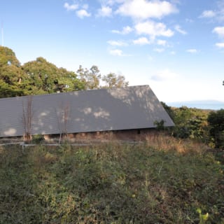 道路側からはほぼ家の屋根のみが見え、プライバシーを確保。画像左側にある玄関から海に向かって屋根が上がり、内部空間も同じように広がっていく