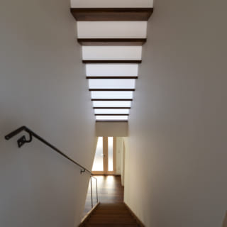 上部の２階からロフトへの階段はポリカーボネート板の蹴上から光が抜けるように計画。１階までを明るくする