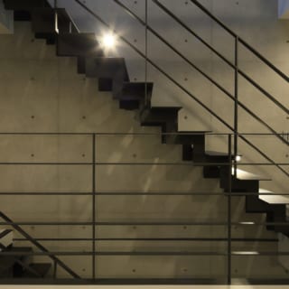 コンクリート打ち放しの壁とブラックアイアンの階段、スポットライトの灯りなど、無機質で統一感のあるスタイリッシュなデザイン