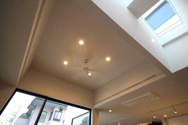 LDK部分の天井はキッチンスペースよりも高くなっているため、開放感がある。天井のトップライトからの光が、白壁に反射して室内をやわらかく照らすよう壁の角度も計算されているのだという