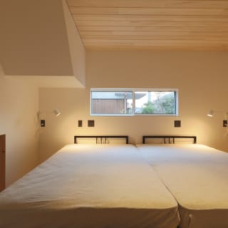 １階寝室。左側はリビング下にある床下収納の一部で、布団を収納したりもできる。枕元にはコンセントや照明のスイッチを配置している
