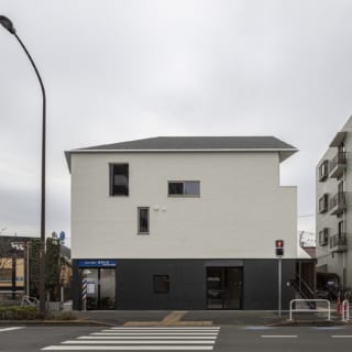 北側、幹線道路から光が丘の家を眺める。店舗やマンションなど、周りの建物とボリュームを合わせ見劣りしないような外観をつくりあげた。テナントが入る1階部分と、2、3階の住居部分とは外壁の色を反転させて視覚的にはっきり分け、それぞれの独立性を高めた