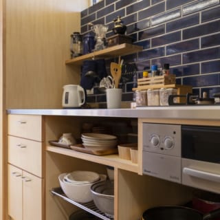 タイル張りのキッチンはかおりさんの設計。棚の一部は底板がステンレス。使った調理器具を熱いまま置ける