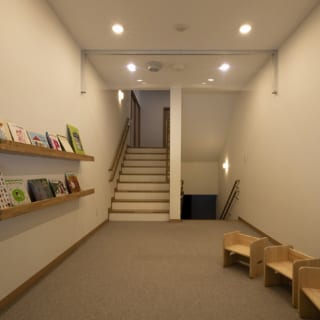 1階から2階に上がる階段の踊り場を利用して計画された図書コーナー。気軽に絵本が読める場所として、園児の人気スポットのひとつとなっている。このスペースの下も有効活用し、1階からアクセスできる倉庫を設けた