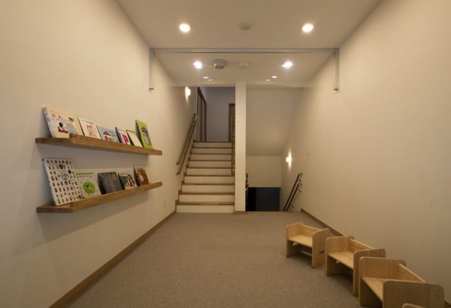 1階から2階に上がる階段の踊り場を利用して計画された図書コーナー。気軽に絵本が読める場所として、園児の人気スポットのひとつとなっている。このスペースの下も有効活用し、1階からアクセスできる倉庫を設けた