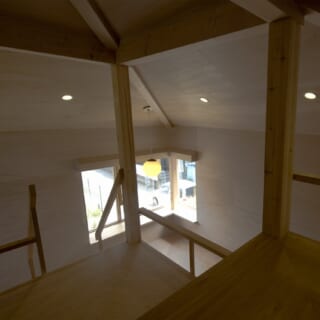 2階の小屋裏収納から下を見下ろす。成長した子どもたちが主に過ごす空間になるだろう2階は、大きな屋根でまるごと覆われる。柱や段差の間から2階全体が見渡せ、天井から屋根が感じられることで、「家の中にいる」という実感が湧くという