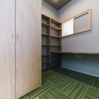 ２階のOさんのワークスペースは緑鮮やかなカーペット敷き。床の一部を乳白色の強化プラスチックで作り、窓からの光をやわらかく下へ導く