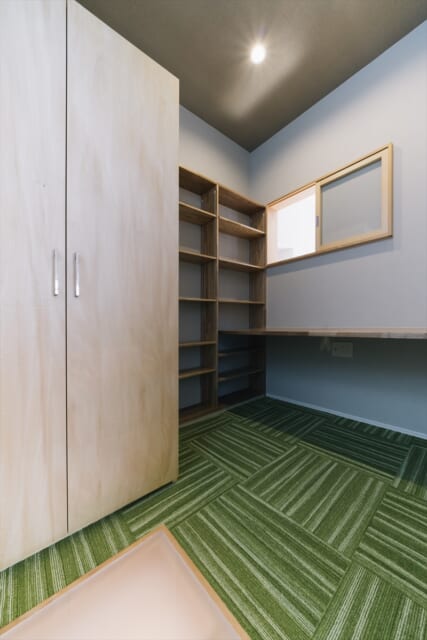 ２階のOさんのワークスペースは緑鮮やかなカーペット敷き。床の一部を乳白色の強化プラスチックで作り、窓からの光をやわらかく下へ導く