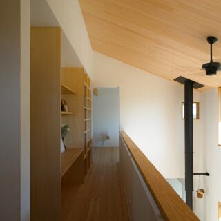 ２階の廊下の笠木は幅広にすることで、バーカウンターのよう。壁面には、本棚とワークスペースを設けた