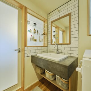 洗面室もオリジナルを造作。モルタルの洗面台やタイル壁がナチュラルで温かな雰囲気