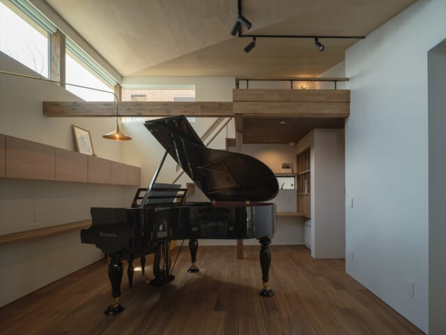 グランドピアノが存在感を示す音楽室。クラシカルな雰囲気をつくるため、ウォールナット調に仕上げた。音楽仲間が集まり演奏会を開くこともあるのだとか。