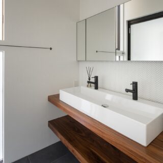 洗面室も洗練されたモダンな空間。鏡の下のヘリンボーン風に整えたタイルが上品なアクセントになっている