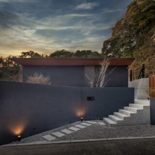 東から見る『Layered house』。背後に小高い山林があるため、災害対策の条例に沿って山林際に擁壁を設ける必要があった。擁壁を全てコンクリートにすると重さが出てシャープな外観を損ねてしまうが、黒いロックフェンスを組み合わせることで洗練された印象に