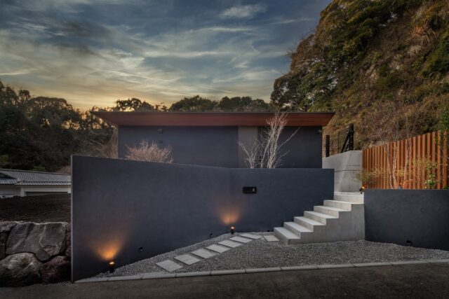 東から見る『Layered house』。背後に小高い山林があるため、災害対策の条例に沿って山林際に擁壁を設ける必要があった。擁壁を全てコンクリートにすると重さが出てシャープな外観を損ねてしまうが、黒いロックフェンスを組み合わせることで洗練された印象に