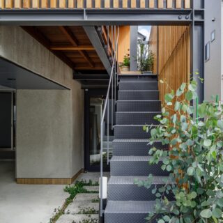 自邸玄関へ続く外階段は木製格子で覆われ、抜群のプライベート感。アプローチの先にはアトリエがある