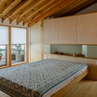 寝室。天井は木の表情を楽しめる現し仕上げ。ウッドデッキに並ぶ植物の緑にも癒やされ、リゾートヴィラのような心地よさ。写真奥は2人分のウォークインクローゼット