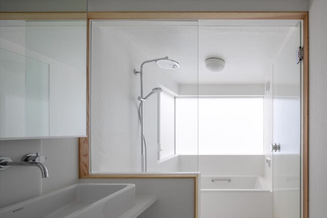 洗面所、浴室。明るい浴室にするため白を基調とした。洗面所との仕切りには強化ガラスを採用。仕切りがガラスなので空間がひとつになり、広々と感じられる