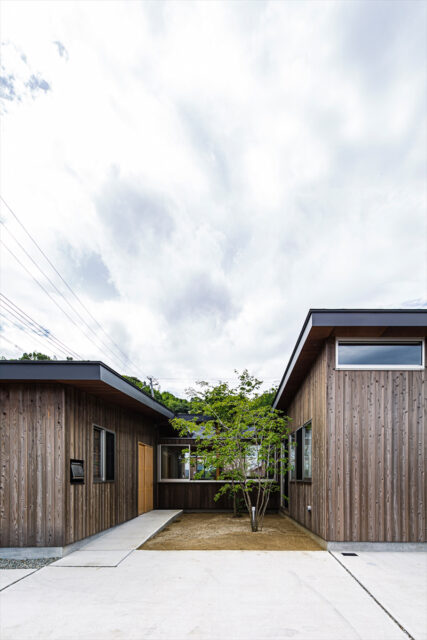 外観。中庭に面した左奥が玄関。屋根の見付を幅広く取ってラインを強調し、建物の奥行き感を強調した