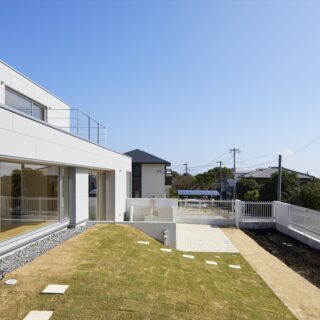 土地の高低差を巧みに利用した、ドッグランを兼ねた庭。芝生の丘のトップは、窓越しに愛犬と視線が合うよう盛り土をして高さを調整。塀際の土のスペースは、小さな菜園として利用しているという
