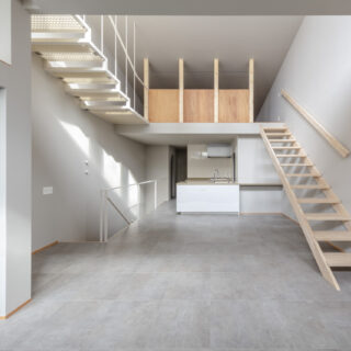 ２階LDK。キッチンの脇の通路は水回りに続く。キッチンの上部にはロフトを配置した。１階の雰囲気と合わせ、床にはコンクリートに似た柄のタイルを採用。収納はKさまがDIYするため空間はシンプルなデザインとし、床暖房など暮らしの快適性を高めるための設備を優先した