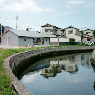 川から家を眺める。道路ではなく川を基準に家を配置したため、周辺の家と比べて川と家の距離が近い。おかげで、水が流れる気配を感じたり、川からの風を余すことなく家に取り入れたりと環境を生かし切ることができた