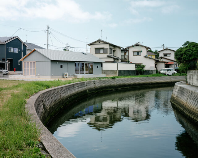 川から家を眺める。道路ではなく川を基準に家を配置したため、周辺の家と比べて川と家の距離が近い。おかげで、水が流れる気配を感じたり、川からの風を余すことなく家に取り入れたりと環境を生かし切ることができた