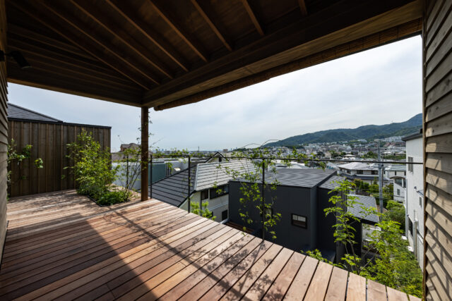 大きな庇の下にある広々とした２階テラスからは六甲の山並みや港が見える。景色をより美しく望めるよう、軒先のかたちを水平にしたり、手すりも目立ちにくい細いものとする配慮も。左端には５つ目の庭である屋上庭も設けている。