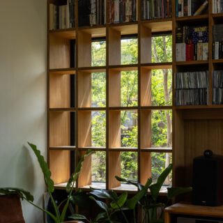 植栽越しに朝の陽光が差す本棚の一角。ソファに座ると窓から入ってくる風を感じられる。