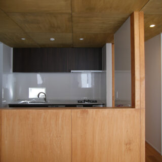 2階子世帯LDKのキッチン。１階も2階も、キッチンの吊戸棚はボタン1つで自動昇降するタイプで、モノを取り出すときに非常に便利。コンロのカウンターは壁付けだが、シンク前に外光が入る小窓があり、明るい光を感じて気持ちよく調理ができる