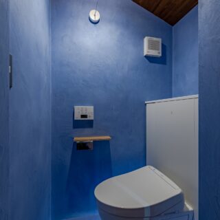 洗面所の先にあるトイレは、ブルーのモルタル素材で塗られた壁が美しい